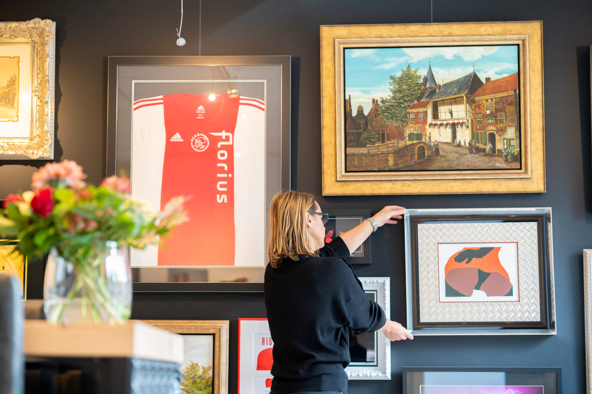 Jacqueline hangt diverse kunstwerken op — van een gesigneerd Ajax-shirt tot een klassiek schilderij